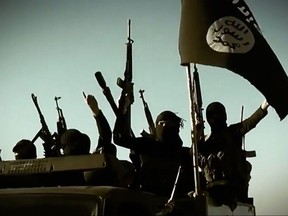 In this file image grab taken from a propaganda video released on March 17, 2014 by the Islamic State allegedly shows ISIL fighters raising their weapons as they stand on a vehicle mounted with the trademark Jihadists flag at an undisclosed location in the Anbar province.