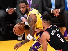 In this Jan. 31, 2020, file photo LeBron James of the Los Angeles Lakers looks to pass under pressure from C.J. McCollum of the Portland Trailblazers in Los Angeles.