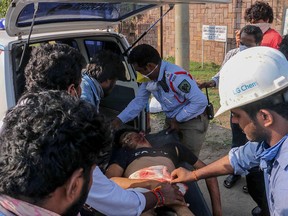 Police personnel and people carry a man (C) that has fainted following a gas leak incident to transport him to a hospital in Visakhapatnam on May 7, 2020.