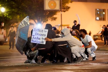 People huddle as they are struck by pepper-balls fired by police during a protest against the deaths of Breonna Taylor by Louisville police and George Floyd by Minneapolis police, in Louisville, Kentucky, May 29, 2020.