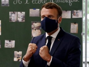 French President Emmanuel Macron, wearing a protective mask, gestures as he speaks to pupils during a visit at the Pierre Ronsard elementary school in Poissy, on May 5, 2020.