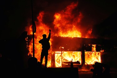 A protester gestures as buildings burn during continued demonstrations against the death in Minneapolis police custody of African-American man George Floyd, in Minneapolis, Minn., May 30, 2020.
