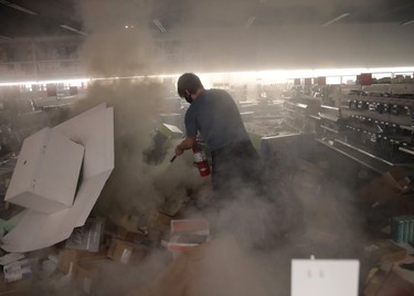 A man tries to put out a fire in a store that was ransacked by looters during protests sparked by the death of George Floyd while in police custody on May 29, 2020 in Minneapolis, Minn.