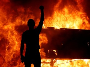 A protester gestures in front of a fire during a demonstration against the death of African-American man George Floyd, in Minneapolis, early May 30, 2020.