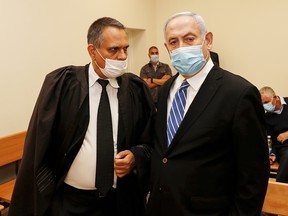 Israeli Prime Minister Benjamin Netanyahu (R), wearing a protective face masks, is pictured inside a courtroom at the district court of Jerusalem on May 24, 2020, during the first day of his corruption trial.