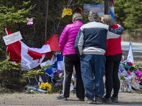 A family pays their respects to victims of the mass killing at a checkpoint in Portapique, N.S., on Friday, April 24, 2020.