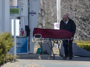 A worker with the medical examiner's office removes the body of Gabriel Wortman from a gas bar in Enfield, N.S. on Sunday, April 19, 2020.