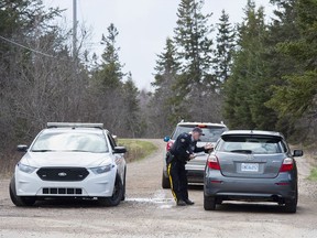 An RCMP officer talks with a local resident before escorting them home at a roadblock in Portapique, N.S., April 22, 2020.