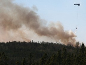 A Department of Natural Resources helicopter, drops water on a wildfire, near Porters Lake, N.S., on Saturday, May 23, 2020.