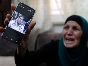 The mother of a Palestinian man with special needs cries as she shows his picture on her mobile telephone, at her home in annexed east Jerusalem, on May 30, 2020.