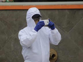 A person wearing a protective suit and gloves takes pictures with his phone during the government-ordered lockdown to halt the spread of COVID-19 in Quito, Ecuador, on Monday, May 4, 2020.