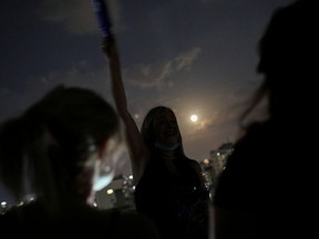 People gather at a rooftop as the Supermoon rise over the city of Caracas in an astronomical event that occurs when the moon is closest to the Earth in its orbit, making it appear much larger and brighter than usual, in Caracas, Venezuela May 7, 2020.