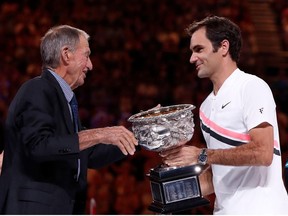 Switzerland's Roger Federer is presented with the trophy by former player Ashley Cooper after winning the final against Croatia's Marin Cilic.
