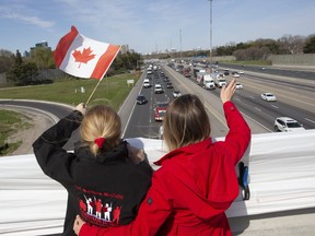 Valerie McGrady gets a hug from her daughter Shannon MacDonald as they acknowledge appreciative motorists from below as they wait for casket of 6 Canadian Armed Forces members that were killed last week off the coast of Greece to pass on Canada's Highway of Heroes in Toronto, May 6, 2020. McGrady lost her son Cpl Matthew McCully in Afghanistan in 2007.