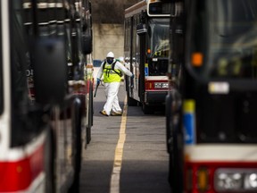 TTC workers wear protective suits inside a bus at the Toronto Transit Commission's Queensway Garage on Evans Ave. near Kipling Ave. in Toronto, Ont. on Thursday, April 16, 2020.
