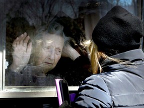Diane Colangelo visits her 86-year-old mother Patricia through a window at the Orchard Villa long-term care home in Pickering, Ont., on Wednesday April 22, 2020.
