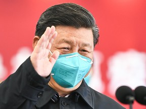 This photo released by China's Xinhua News Agency shows Chinese President Xi Jinping wearing a mask as he waves to a coronavirus patient and medical staff via a video link at the Huoshenshan hospital in Wuhan, in China's central Hubei province on March 10, 2020.