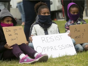 Young protesters hold signs during anti-racist and anti-police brutality demonstration in Montreal on May 31, 2020.