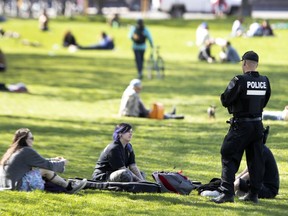 An SPVM officer speaks with people who gathered at a busy Jeanne-Mance Park on May 18 during the COVID-19 pandemic.