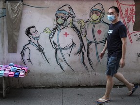 A resident wear a mask while passing the graffiti of Nurses fight against new coronavirus on June 16, 2020 in Wuhan, Hubei Province, China.