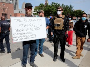 Armed men, one carrying a "The Boogaloo stands with George Floyd" sign, are seen as protesters rally against the death in Minneapolis police custody of George Floyd, in Detroit, Michigan, May 30, 2020.