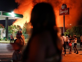 People watch as a Wendy’s burns following a rally against racial inequality and the police shooting death of Rayshard Brooks, in Atlanta, Georgia, June 13, 2020.
