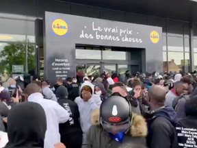 People who gathered outside a Lidl store react after pepper spray was used as the store is due to sell the PlayStation 4 for 95 Euros, in Orgeval, France June 17, 2020 in this still image obtained from a social media video.
