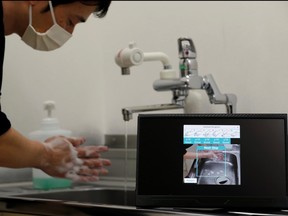 Fujitsu senior researcher Genta Suzuki washes his hands as he demonstrates AI-camera recognition technology that checks whether people follow six handwashing steps recommended by the Japanese health ministry during an interview with Reuters at the company's research and development laboratory in Kawasaki, Japan June 17, 2020.