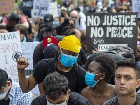 Anti-racism demonstrators take a knee in front of the U.S. Conuslate in Toronto during a march on Saturday, June 6, 2020.