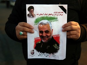 A man holds a picture of late Iranian Major-General Qassem Soleimani.