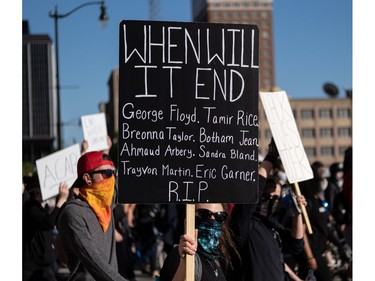 TOPSHOT - Protesters hold signs in Detroit, Michigan on May 31, 2020 following a night of protests that saw several arrests and uses of tear gas by the Detroit Police department on what was peaceful protesting. - Thousands of National Guard troops patrolled major US cities after five consecutive nights of protests over racism and police brutality that boiled over into arson and looting, sending shock waves through the country. The death Monday of an unarmed black man, George Floyd, at the hands of police in Minneapolis ignited this latest wave of outrage in the US over law enforcement's repeated use of lethal force against African Americans -- this one like others before captured on cellphone video. (Photo by SETH HERALD / AFP)