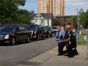 Minneapolis Police Chief Medaria Arradondo (R) kneels as the remains of George Floyd are taken to a memorial service in his honour on June 4, 2020, in Minneapolis.