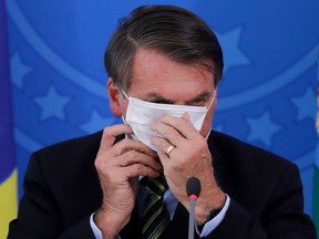 In this file photo taken on March 18, 2020, Brazilian President Jair Bolsonaro covers his face with a face mask during a press conference regarding the COVID-19 pandemic at the Planalto Palace, Brasilia.