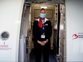 A cabin crew member wearing a protective face mask waits at the entrance of a Brussels Airlines plane, at Brussels Airport, in Zaventem, on June 15, 2020.