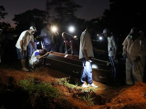 A man reacts as the coffin of his father, who died from COVID-19, is prepared to be buried at Vila Formosa cemetery, Brazil's biggest cemetery, in Sao Paulo, Friday, June 19, 2020.