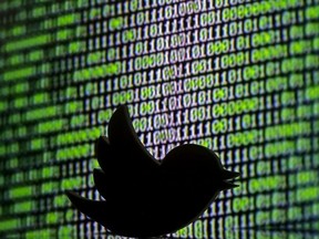 A 3D printed Twitter logo is seen in front of a displayed cyber code in this illustration taken March 22, 2016.