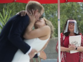 Wedding Commissioner Ruth Lipton, wearing a protective face shield, looks on after marrying Nikki Alexis and Roni Jones during a city of Vancouver micro-wedding pilot program outside of Vancouver City Hall, Friday, June 19, 2020.