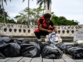 A protester sets up bags representing bodies during a funeral procession demonstration against the reopening of Florida, in Miami, on May 27, 2020.