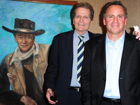 Patrick (L) and Ethan Wayne, sons of the iconic American film star John Wayne, pose beside a painting of their father at an auction preview, October 3, 2011 in Los Angeles, California.