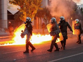 Riot police walk past flames as they clash with protesters outside the U.S. embassy in Athens, June 3, 2020.