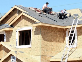 This undated file photo shows contractors working on the roof of a house under construction.