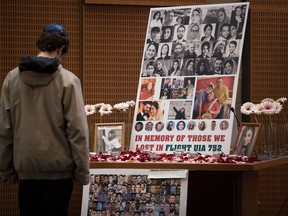 A man pauses to look at photographs of some of the people who died in the downing of Ukrainian Airlines Flight 752 in Iran, during a vigil for the victims of the flight at the Har El synagogue in West Vancouver on Sunday Jan. 19, 2020.