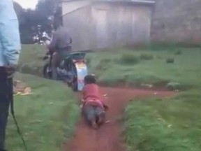 Kenya police shared this photo taken from a video of a woman being dragged by a motorbike.