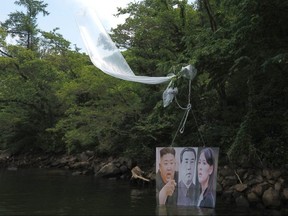 A balloon carrying a banner with portraits of North Korean leader Kim Jong Un (left), the late leader Kim Il Sung (middle) and Kim Yo Jong is caught on a tree after being launched by activists in Hongcheon on June 23, 2020.