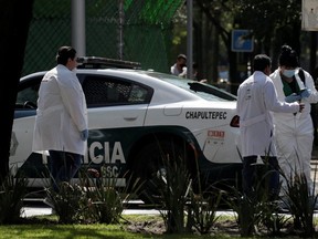 Forensic officers check a police car with a shattered rear window in the area near the scene of a shooting in Mexico City, Friday, June 26, 2020.