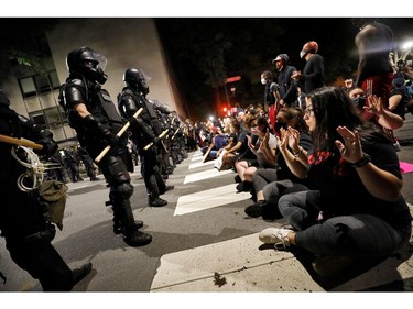Protesters sit in the street facing a line of riot policemen during nationwide unrest following the death in Minneapolis police custody of George Floyd, in Raleigh, North Carolina, U.S. May 31, 2020. Picture taken May 31, 2020. REUTERS/Jonathan Drake ORG XMIT: JAD107