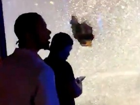 People pass by shattered glass on a shopfront after a shooting in Minneapolis June 21, 2020, in this picture obtained from social media video.