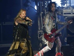 Motley Crue lead singer Vince Neil points to the crowd as he runs past bassist Nikki Sixx (right) during a concert at the Molson Amphitheatre in Toronto, Aug. 11, 2014.