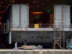 A Seaspan Vancouver Shipyards worker walks past a barge under construction in North Vancouver, B.C., on Wednesday November 2, 2011. Canada's sharply divided shipbuilding industry was dealt a surprise this morning as two competing yards announced plans to team up to win a multibillion-dollar contract to build a new polar icebreaker for the Canadian Coast Guard.