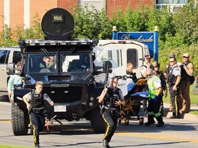 Police and RCMP officers survey the area of a shooting in Fredericton on Friday, August 10, 2018.